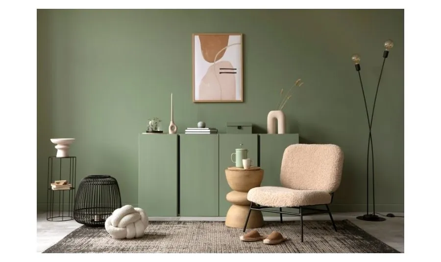 Silla beige de textura suave en una sala con paredes verdes, mesa auxiliar de madera y decoración moderna que refleja interiorismo en Zaragoza.